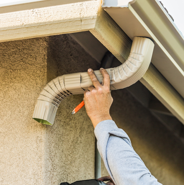 Worker attaching aluminum rain gutter